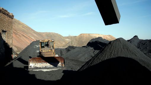 Bagr u vytěžených hromad uhlí.