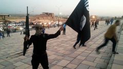 File photo of a fighter of the ISIL holding a flag and a weapon on a street in Mosul