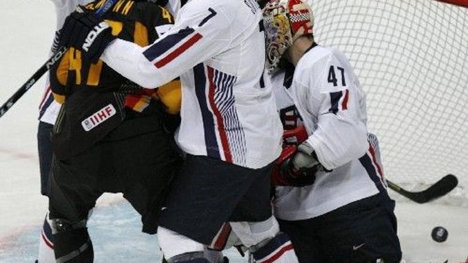 Německý hokejista Florian Busch (vzadu) sleduju puk, který propadl za záda americkému brankáři Johnu Grahamovi (47).