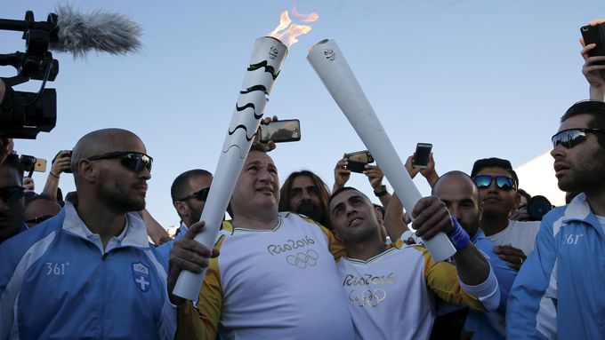 Ibrahim Hussejn (vpravo) přebírá olympijský oheň od předsedy Hellénského olympijského výboru Spyrose Kapralose.
