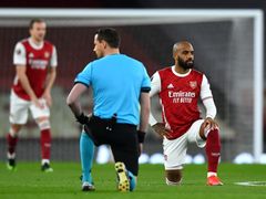 Rozhodčí a hráč Arsenalu Alexandre Lacazette klečí před čtvrtfinále EL Arsenal - Slavia