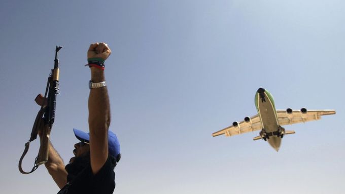 Jeden z povstalců na jihozápadě Libye zdraví letadlo z Benghází, které přistává na improvizované letištní ploše. Otevření letiště umožní povstalcům v pohoří Džebel Nafúsa nedaleko Tripolisu doplnit zásoby potravin a zbraní.