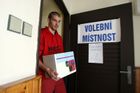 Člen volební komise Jakub Piškora přináší do volební místnosti v obci Tuchlovice zapečetěnou volební urnu.