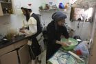 Pohled do domácnosti ultraortodoxních Židů. Muž v tradičním náboženském oblečení připravuje se svou ženou večeři před šábesem.