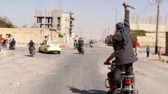Man holds up a knife as he rides on the back of a motorcycle touring the streets of Tabqa city with others in celebration after Islamic State militants took over Tabqa air base, in nearby Raqqa city
