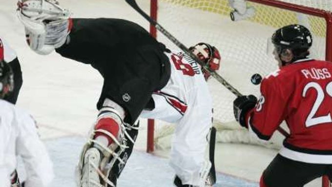 Kanadský gólman Martin Brodeur (v bílém) se v zápase se Švýcarskem marně vrhá po puku, který skončil v jeho brance. Vpravo je Martin Pluss.