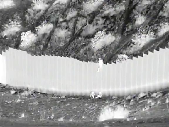 Snímek z kamery, jež zachytila, jak pašeráci hodili dvě batolata přes hraniční bariéru.