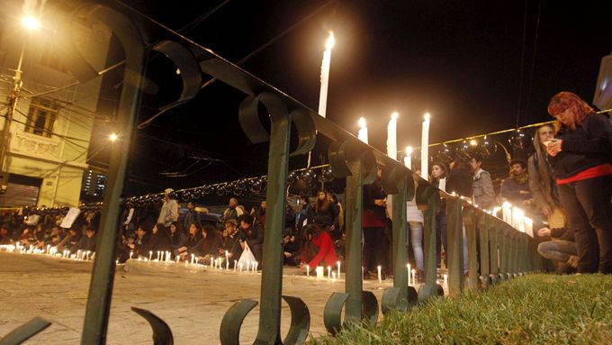 Lidé zapalují na památku zemřelých studentů svíčky.