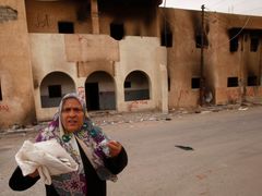 Žena jde kolem zničené budovy v Tobruku, ve městě v severovýchodní části Libye poblíž hranic s Egyptem.