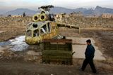 Chlapec míjí zničenou helikoptéru ruské výroby. Snímek je z Kábulu z 5. února 2009.