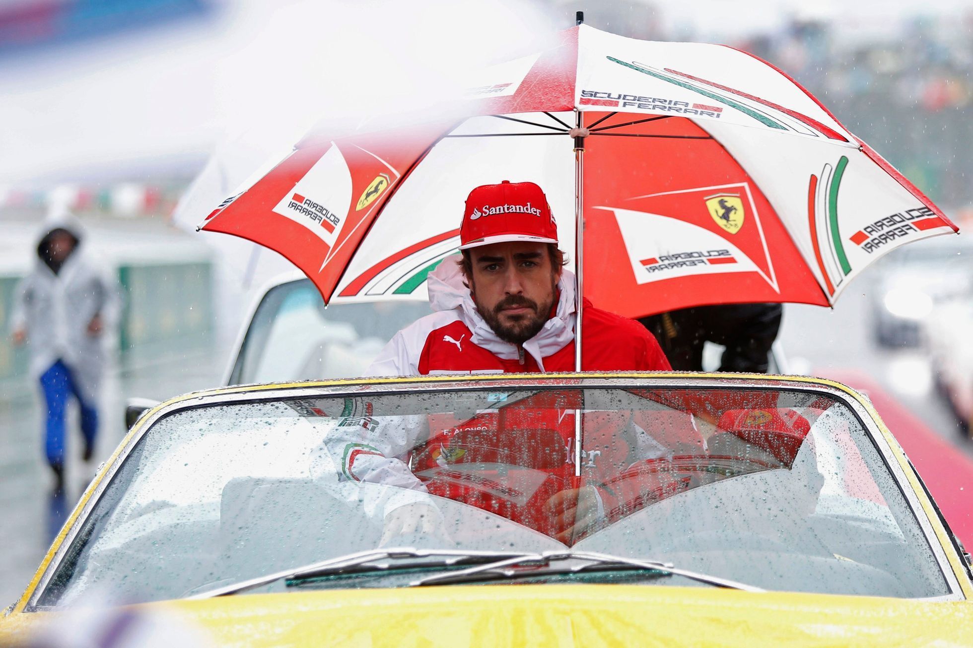 Ferrari Formula One driver Fernando Alonso of Spain sits under an umbrella during the drivers' parade ahead of the Japanese F1 Grand Prix at the Suzuka Circuit