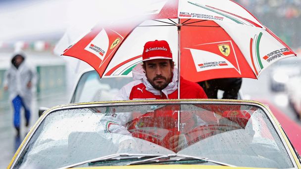 Ferrari Formula One driver Fernando Alonso of Spain sits under an umbrella during the drivers' parade ahead of the Japanese F1 Grand Prix at the Suzuka Circuit