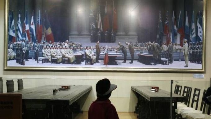 Číňan si v muzeu prohlíží obraz, zachycující kapitulaci japonských okupantů v čínském Nankingu v roce 1945. Válka i po více než 60 letech stále zatěžuje vztahy mezi Pekingem a Tokiem.