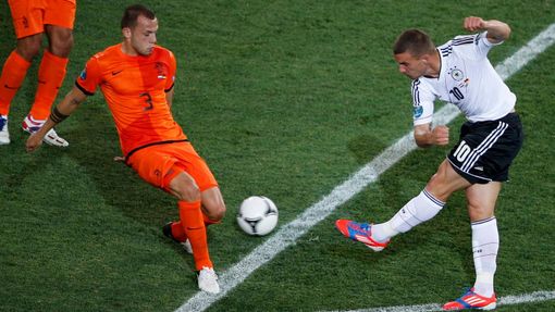 Lukas Podolski se snaží pálit přes Johna Heitingu během utkání Nizozemska s Německem ve skupině B na Euru 2012.