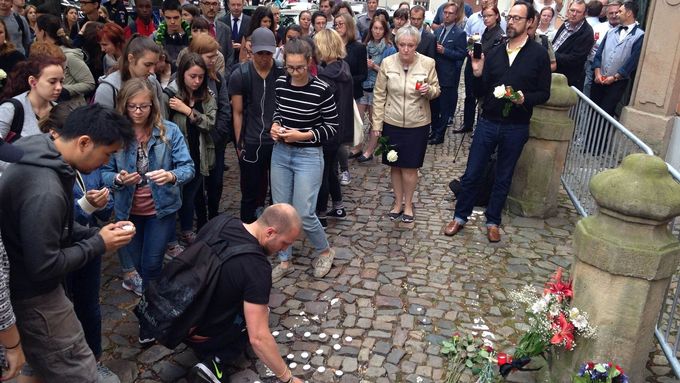 Lidé před francouzským velvyslanectvím zapalují svíčky.