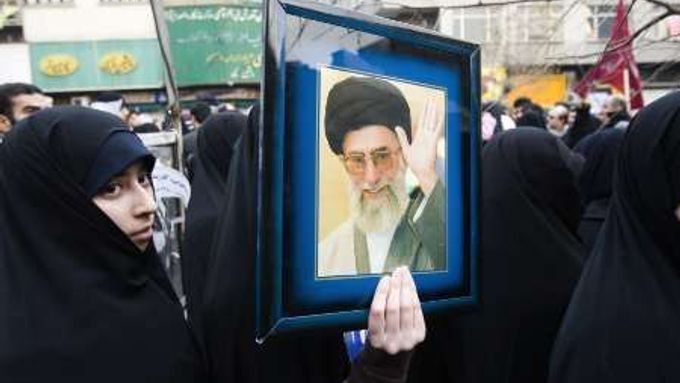 Žena na vládou organizované demonstraci drží v rukou fotku ajatolláha Chameneího..