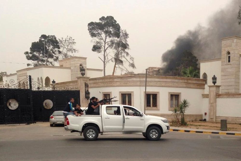 Ozbrojenci před budovou libyjského parlamentu, ze které stoupá kouř.