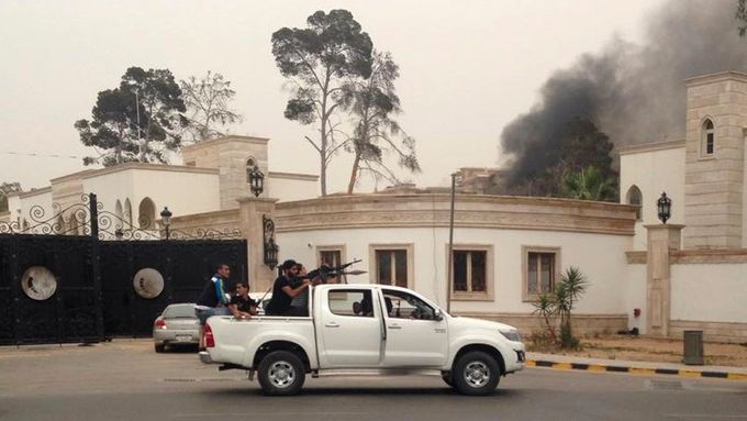 Ozbrojenci před budovou libyjského parlamentu, ze které stoupá kouř.