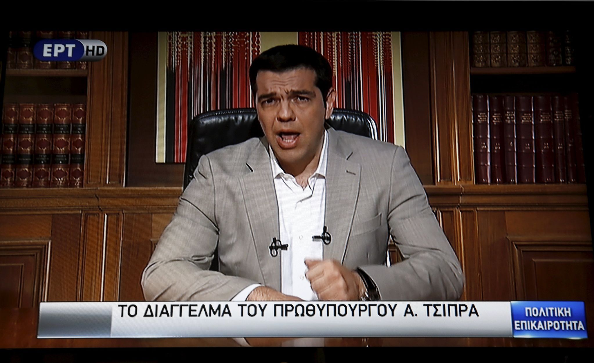 Greek Prime Minister Alexis Tsipras is seen on a television monitor while addressing the nation in Athens, Greece