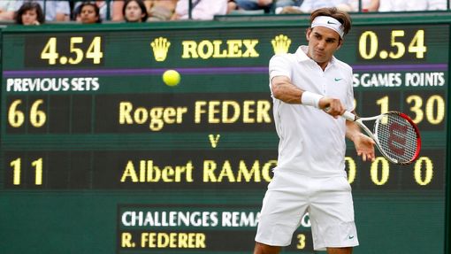 Švýcarský tenista Roger Federer odráží míček během utkání se Španělem Albertem Ramosem v 1. kole Wimbledonu 2012.
