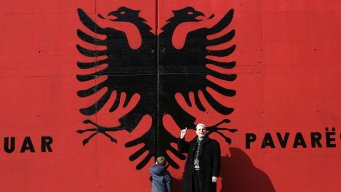 Kosovo Albanians stand in front of a giant Albanian flag with the words "Happy Independence" painted on a wall in the south Kosovo town of Kacanik February 11, 2008. The European Union is set to complete authorisation of a big supervisory mission in Kosovo this week, just before the territory is expected to declare independence from Serbia, diplomats and EU officials said. REUTERS/Hazir Reka (SERBIA)