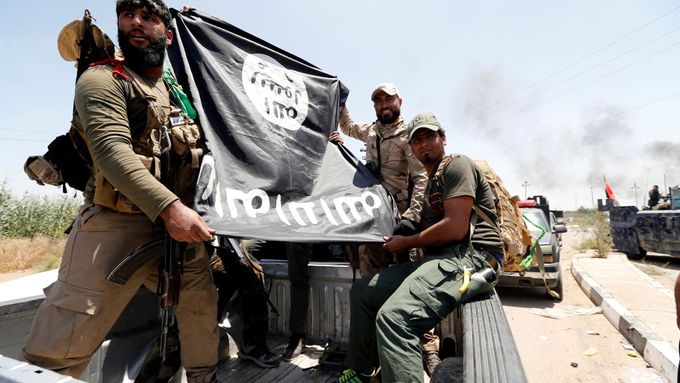 Irácké jednotky drží ukořistěnou vlajku džihádistů z Islámského státu, ilustrační foto.