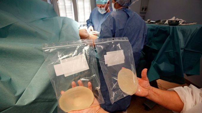 Sestra ukazuje očištěné defektní silikonové prsní implantáty společnosti PIP. Chirurgický tým doktora Denise Boucqua (uprostřed) je na klinice v Nice právě vyjmul z pacientky. Snímek z 5. ledna 2012.