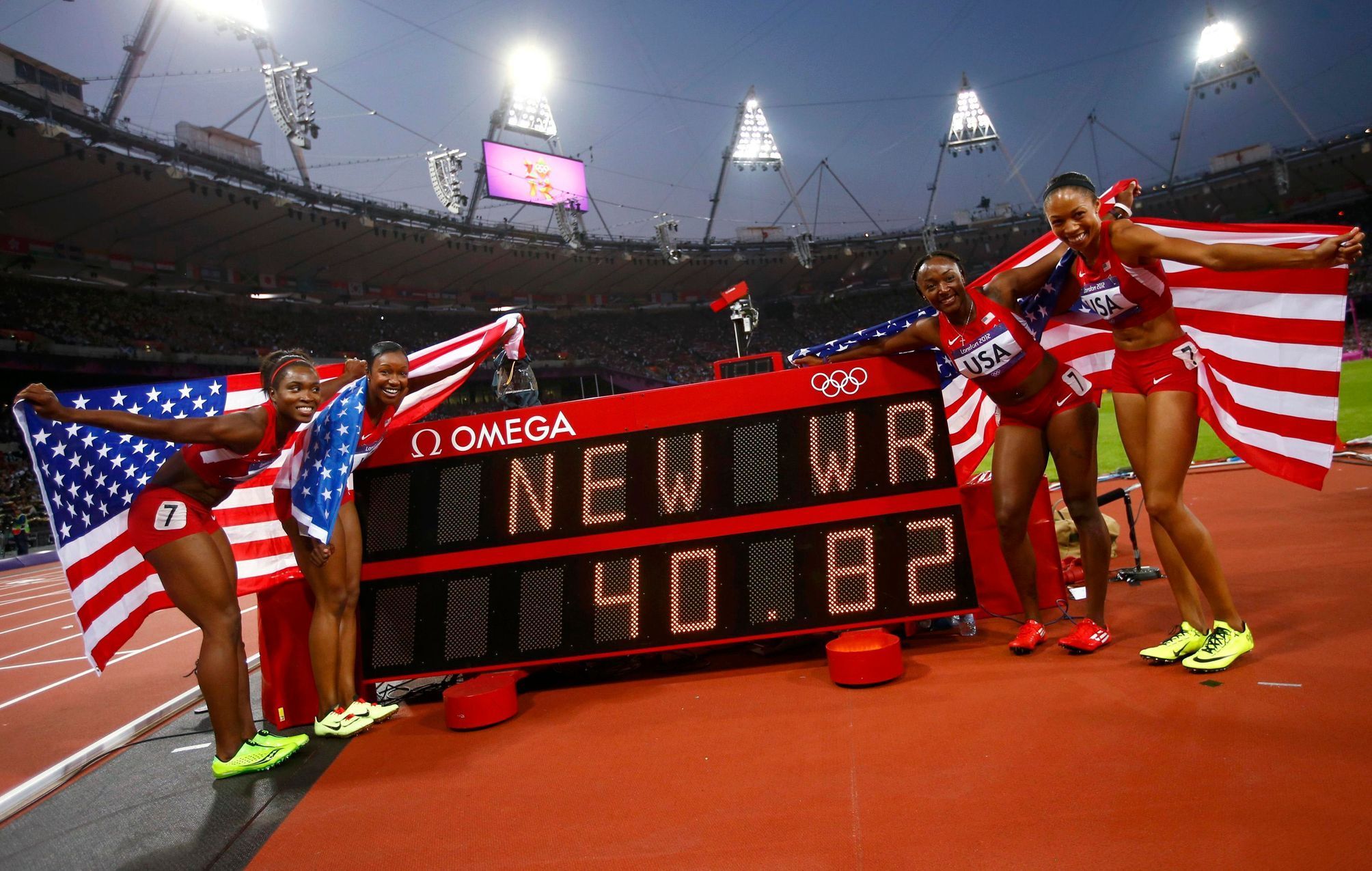 Americká štafeta na 4x100 metrů se usmívá u výsledkové tabule se svým světovým rekordem