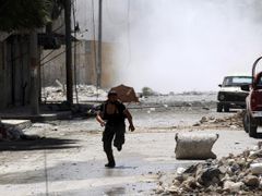 Příslušník povstalecké Svobodné syrské armády běží během bojů v Aleppu do úkrytu