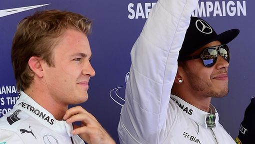 Mercedes Formula One driver Lewis Hamilton (R) of Britain gestures after taking the pole position, accompanied by second-fastest teammate Nico Rosberg of Germany, at the