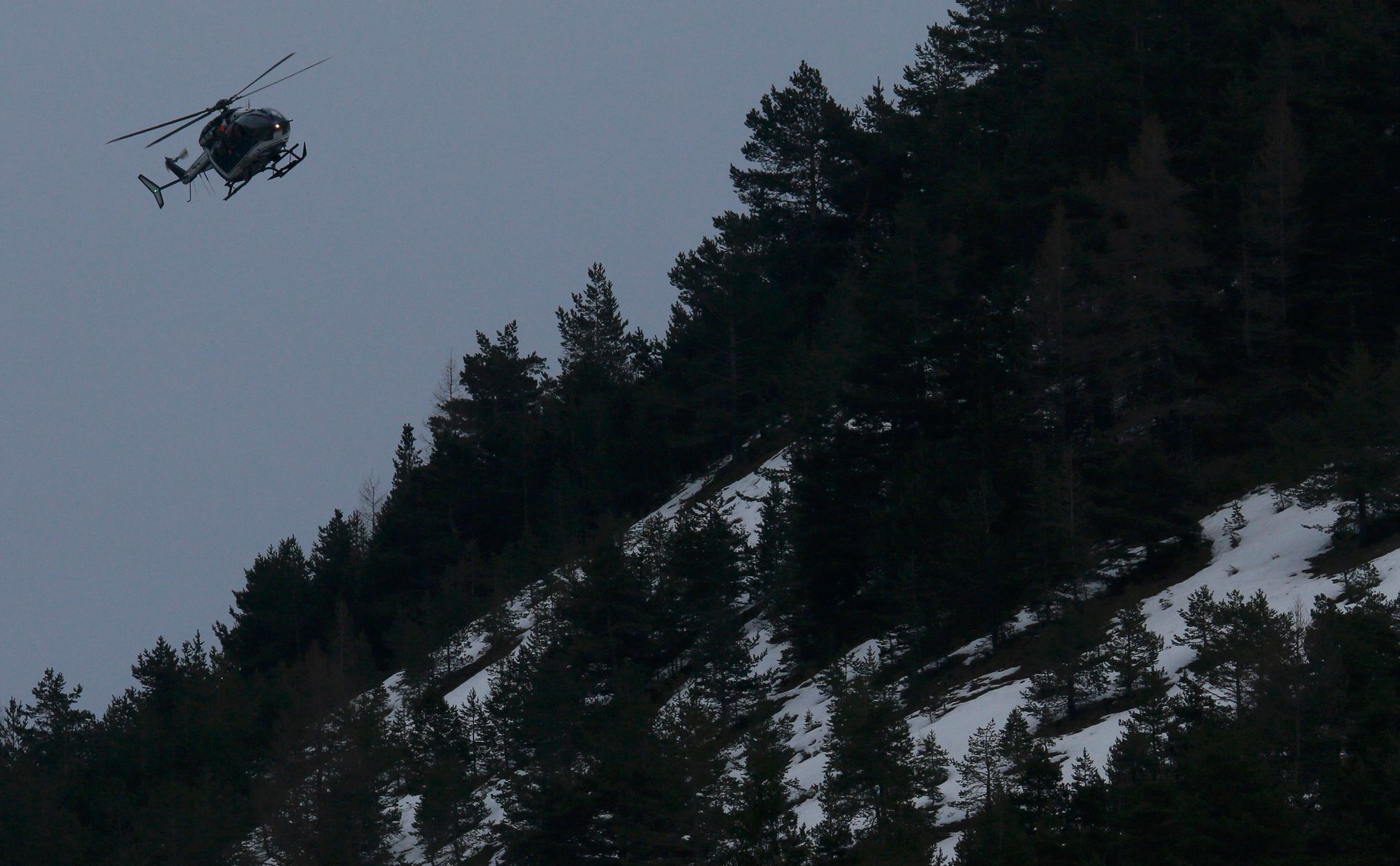 A rescue helicopter from the French Gendarmerie flies over the French Alps during a rescue operation next to the crash site of an Airbus A320