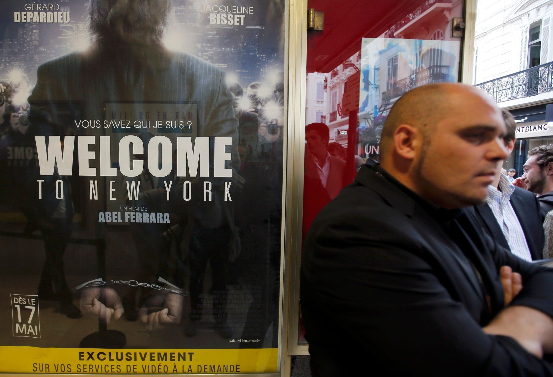 A man stands next to a poster of the film &quot;Welcome to New York&quot; directed by Abel Ferrara at a movie theatre ahead of a premiere screening during the 67th Cannes Film Festival in Cannes