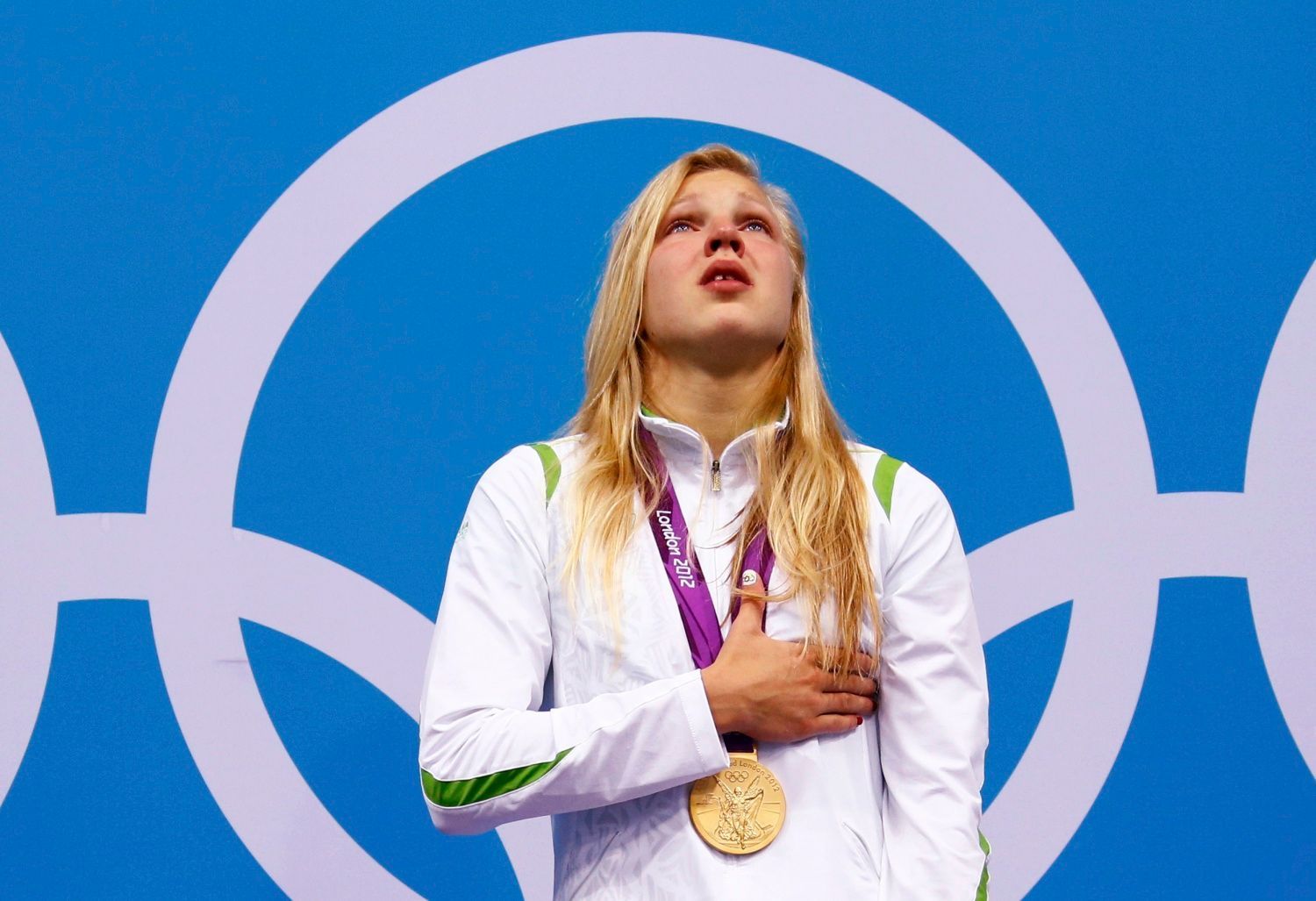 Litevská plavkyně Ruta Meilutyteová zpívá dojatě hymnu se zlatou medailí na krku za 100metrů prsařského závodu na OH 2012 v Londýně.