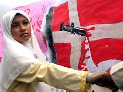 Protesty neustávají ani v Asii. Žena v indonéském Banda Ačehu s dánskou vlajkou. Dánové mezitím vyzvaly své obyvatele, aby z této země co nejdříve odjeli