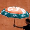 A court boy holds an umbrella during the women's singles match betwween Simona Halep of Romania and Evgeniya Rodina of Russia at the French Open tennis tournament at the Roland Garros stadium in Paris