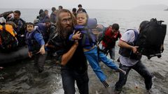 Dobrovolník pomáhá z lodi syrskému dítěti.