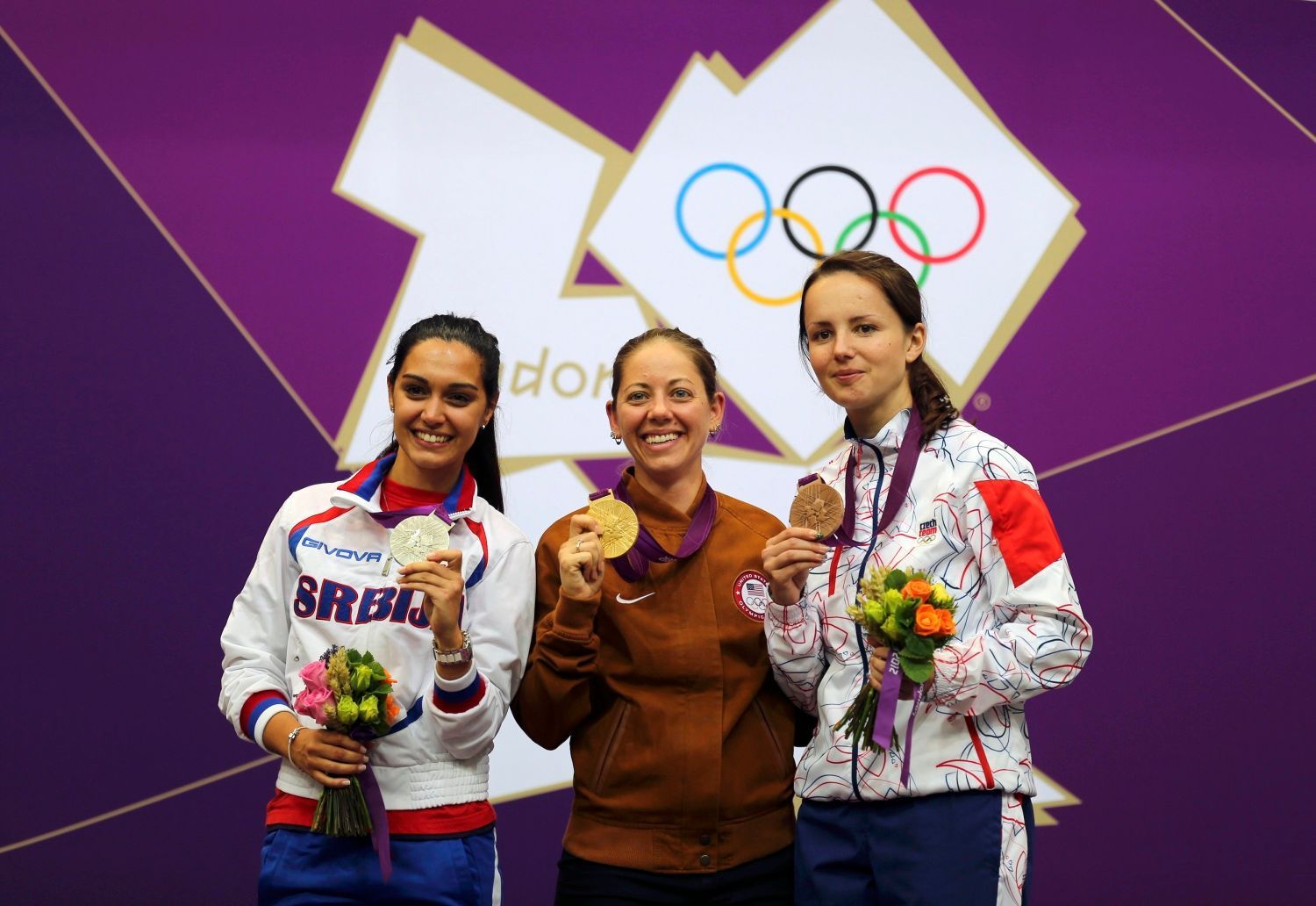 Česká střelkyně Adéla Sýkorová (vpravo) pózuje s bronzovou medailí za malorážku na 50 metrů na OH 2012 v Londýně. Vlevo je stříbrná Srbka Ivana Maksimovičová a uprostřed zlatá Američanka Jamie Lynn Grayová.