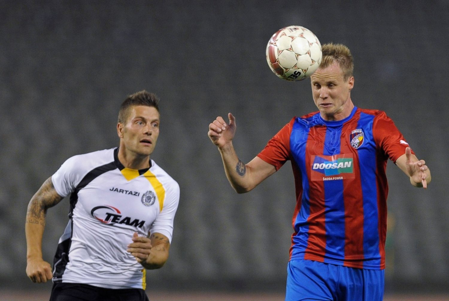 Fotbalista Viktorie Plzeň David Limberský hlavičkuje před Benjaminem De Ceulaerem v utkání Evropské ligy 2012/13 s Lokerenem.