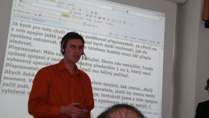Zdeněk Bumbálek z ČVUT předvádí, že slova, jež říká, se po internetu přenesou k přepisovateli, který je zapíše, což je okamžitě vidět v internetovém prohlížeči promítnutém v pozadí.