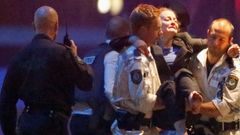 Záchranáři vynášejí z kavárny zraněnou ženu.