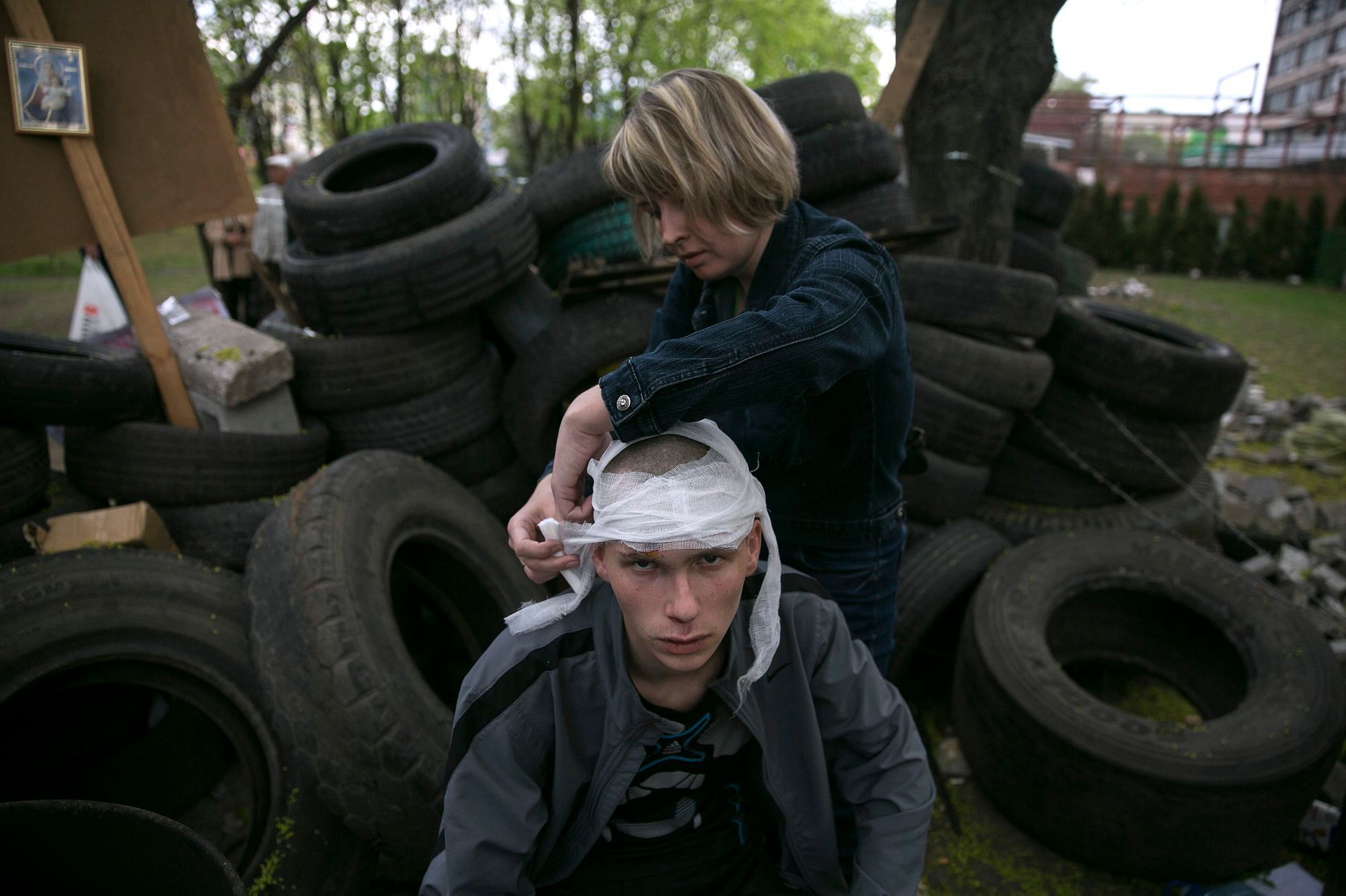 A woman bandages the head of a pro-Russian activist injured outside the Mariupol town hall, East Ukraine
