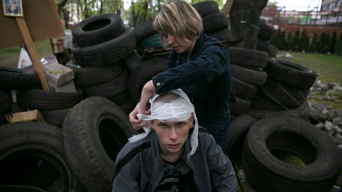 Žena ošetřuje zraněného proruského ativistu v Mariupolu na východní Ukrajině.