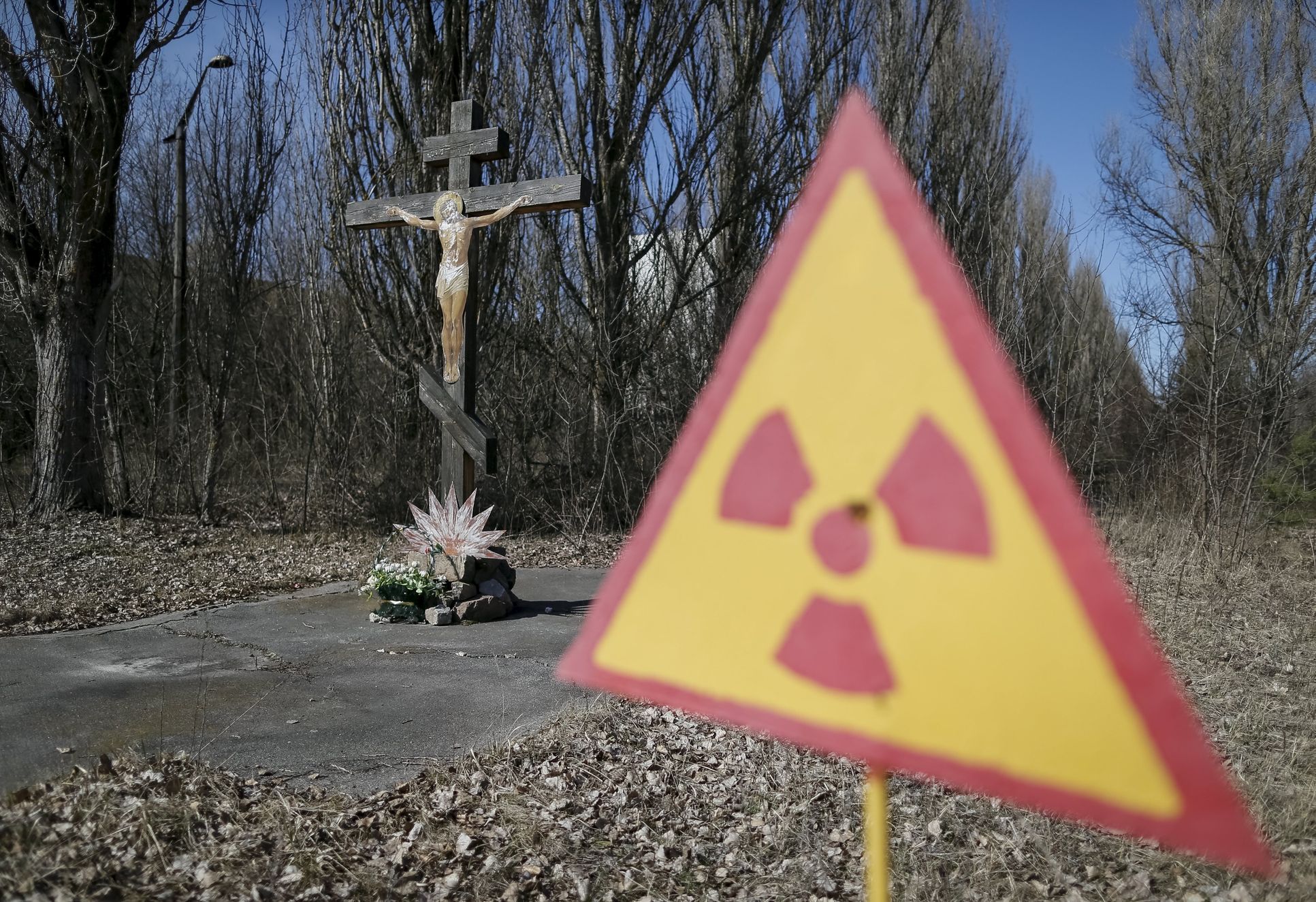 Kristus na kříži a značka upozorňující na radiaci u opuštěného města Pripjať nedaleko Černobylu.