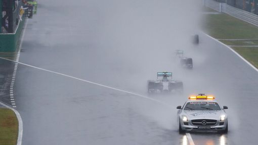 Mercedes Formula One driver Nico Rosberg of Germany leads team mate Lewis Hamilton of Britain behind a safety car as they start the first lap of the rain-affected Japanes