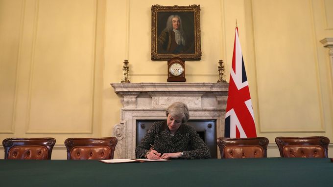 Theresa Mayová podepisuje oficiální dopis Donaldu Tuskovi o aktivaci článku 50 lisabonské smlouvy, v pozadí portrét prvního britského premiéra Roberta Walpolea.