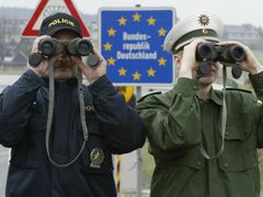 File picture shows Petr Wolf (L) a Czech Republic's border police officer and his German counterpart Marcel Pretzsch as they watch the German-Czech unguarded border zone near the German village of Zinnwald, around 40 kilometres south of Dresden April 23, 2004.