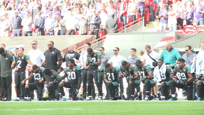 Protest proti Trumpovi: Hráči amerického fotbalu z týmů Jacksonville Jaguars a Baltimor Ravens si klekli a drželi se při americké hymně.