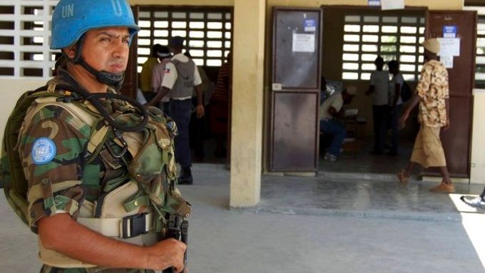 Voják mise OSN hlídá průběh hlasování před volební místností v Port-au-Prince