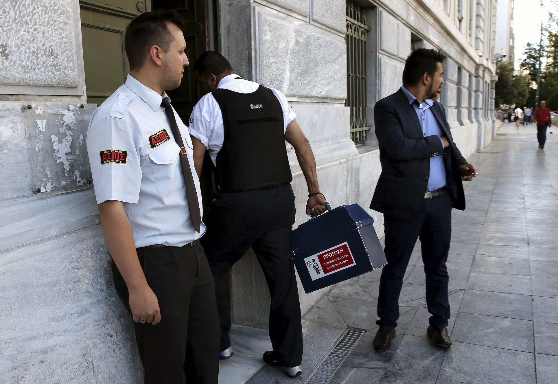 Ostraha vnáší hotovost do pobočky Řecké národní banky.