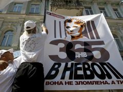 Přívrženec vězněné expremiérky Julije Tymošenkové vyvěšuje plakát s jejím portrétem.